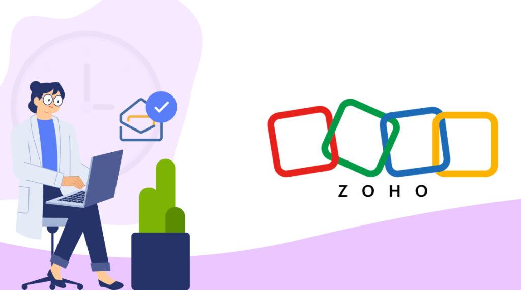 A female scientist in glasses, who is working at her laptop, is sitting next to the Zoho logo