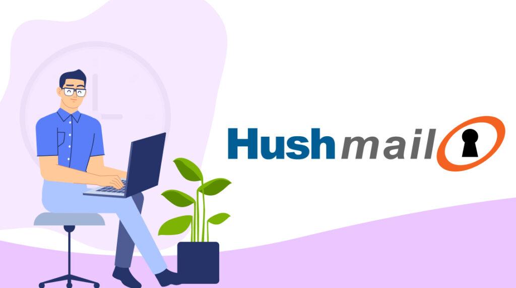 A programmer in a blue shirt, who is working at the computer, is sitting next to the Hushmail logo
